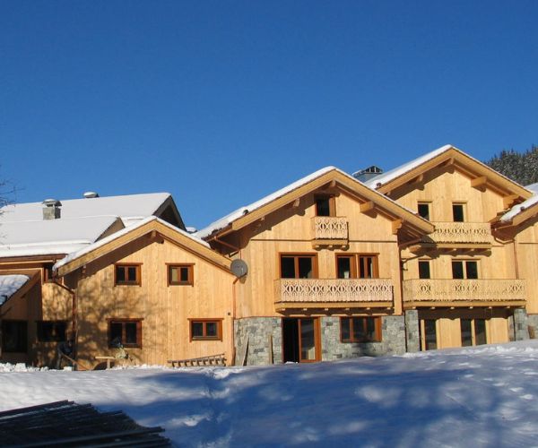 Chalets en bois massif construits par Doxar France dans un environnement montagnard enneigé.