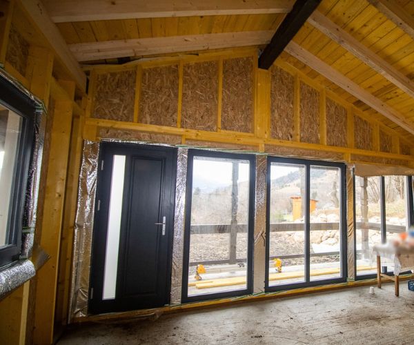 Intérieur d’une maison bois Doxar en cours d’isolation, montrant l’ossature et les finitions.