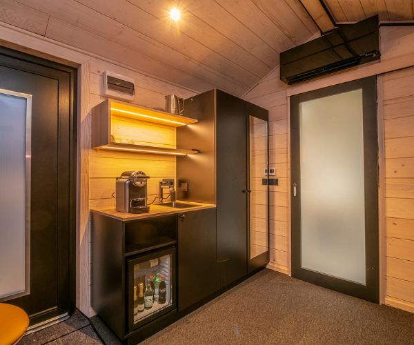 Cuisine équipée et éclairée d’une tiny house Doxar en bois scandinave.