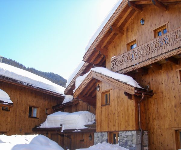 Cour intérieure de chalets en bois avec balcons sculptés et épais manteaux de neige.