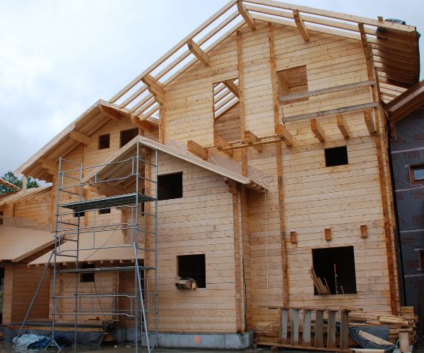 Élévation d’un bâtiment en bois avec échafaudage, murs en madriers en cours.