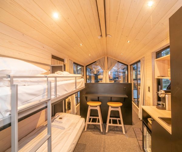 Intérieur d’une tiny house Doxar avec lits superposés et espace repas minimaliste.