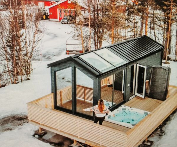 Tiny house Doxar en bois avec terrasse et spa extérieur dans un décor enneigé.