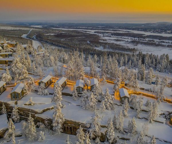 Tiny houses Doxar au cœur d’un paysage enneigé en Suède, éclairées au coucher du soleil.
