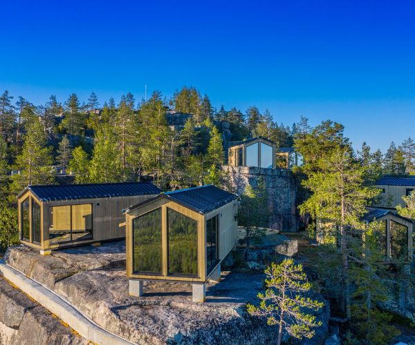 Ensemble de tiny houses Doxar construites sur un site rocheux entouré de pins en Suède.